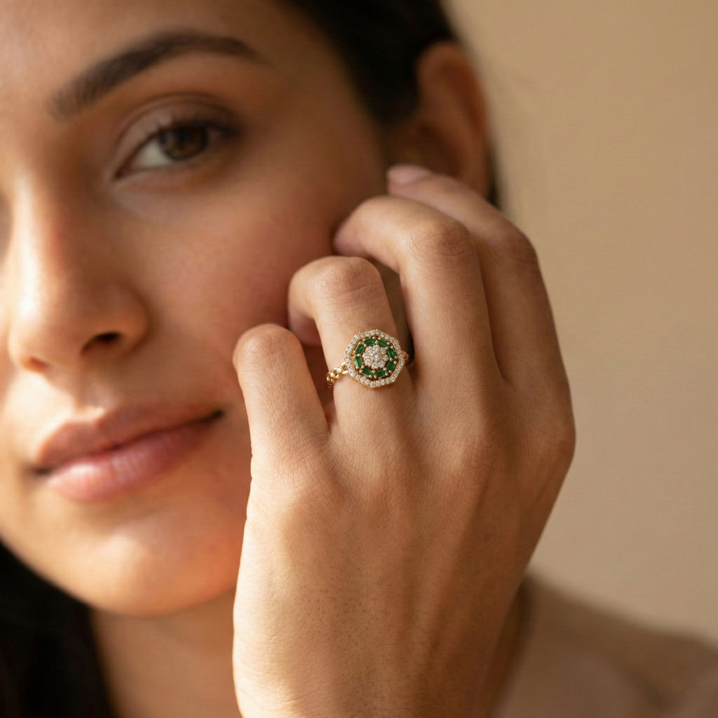 Close-up of a woman's hand wearing a green gemstone ring on a neutral background