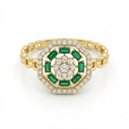 Gold ring with emeralds and diamonds on a white background