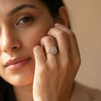 Close-up of a woman's hand wearing a gold ring with a diamond design.