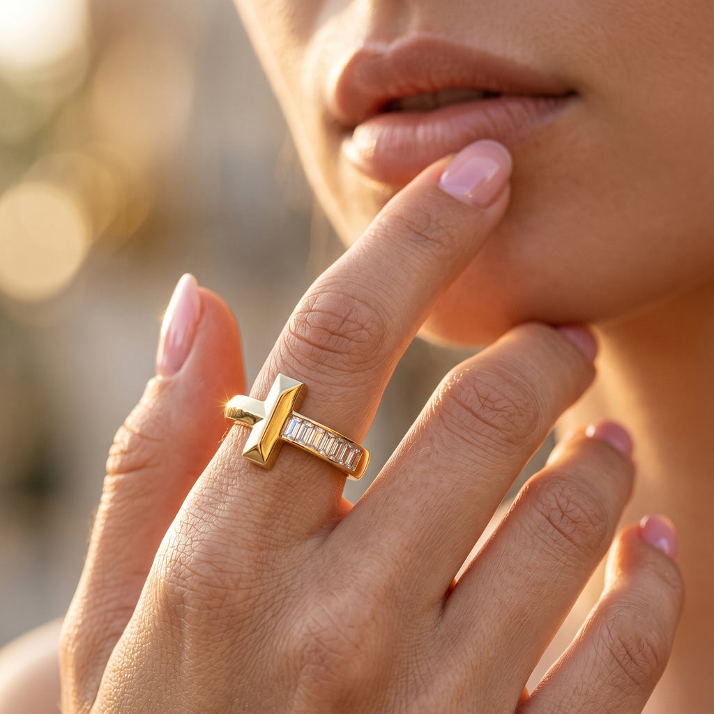 Extreme close-up of a feminine hand gently touching the face, showcasing a detailed UNO 18k yellow gold ring with a T motif and sparkling baguette stones.
تصوير ماكرو قريب لإيد موديل بتلمس وشها برقة، ولابسة خاتم أونو دهب عيار 18 بتصميم حرف T وفصوص باجيت بتلمع.