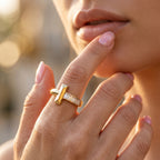 Extreme close-up of a feminine hand gently touching the face, showcasing a detailed UNO 18k yellow gold ring with a T motif and sparkling baguette stones.
تصوير ماكرو قريب لإيد موديل بتلمس وشها برقة، ولابسة خاتم أونو دهب عيار 18 بتصميم حرف T وفصوص باجيت بتلمع.