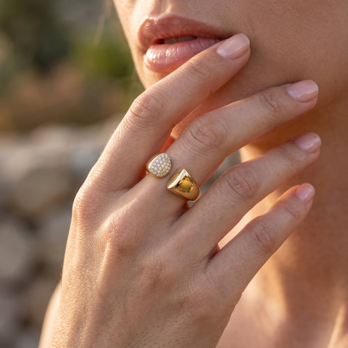 Close-up macro shot of the UNO 18k yellow gold open ring on a woman's hand, showcasing the sharp contrast between the radiant stones and polished gold.
صورة قريبة جداً لخاتم أونو المفتوح عيار 18 على إيد موديل، بتبرز التباين بين لمعة الدهب والفصوص.