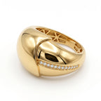 A high-polish UNO 18k yellow gold bombe ring showing its sculptural crossover dome with a diagonal channel of sparkling stones.
خاتم أونو بومبيه دهب أصفر عيار 18 بلمعان قوي، بيبين التصميم المتداخل والمسار المائل المرصع بالفصوص.