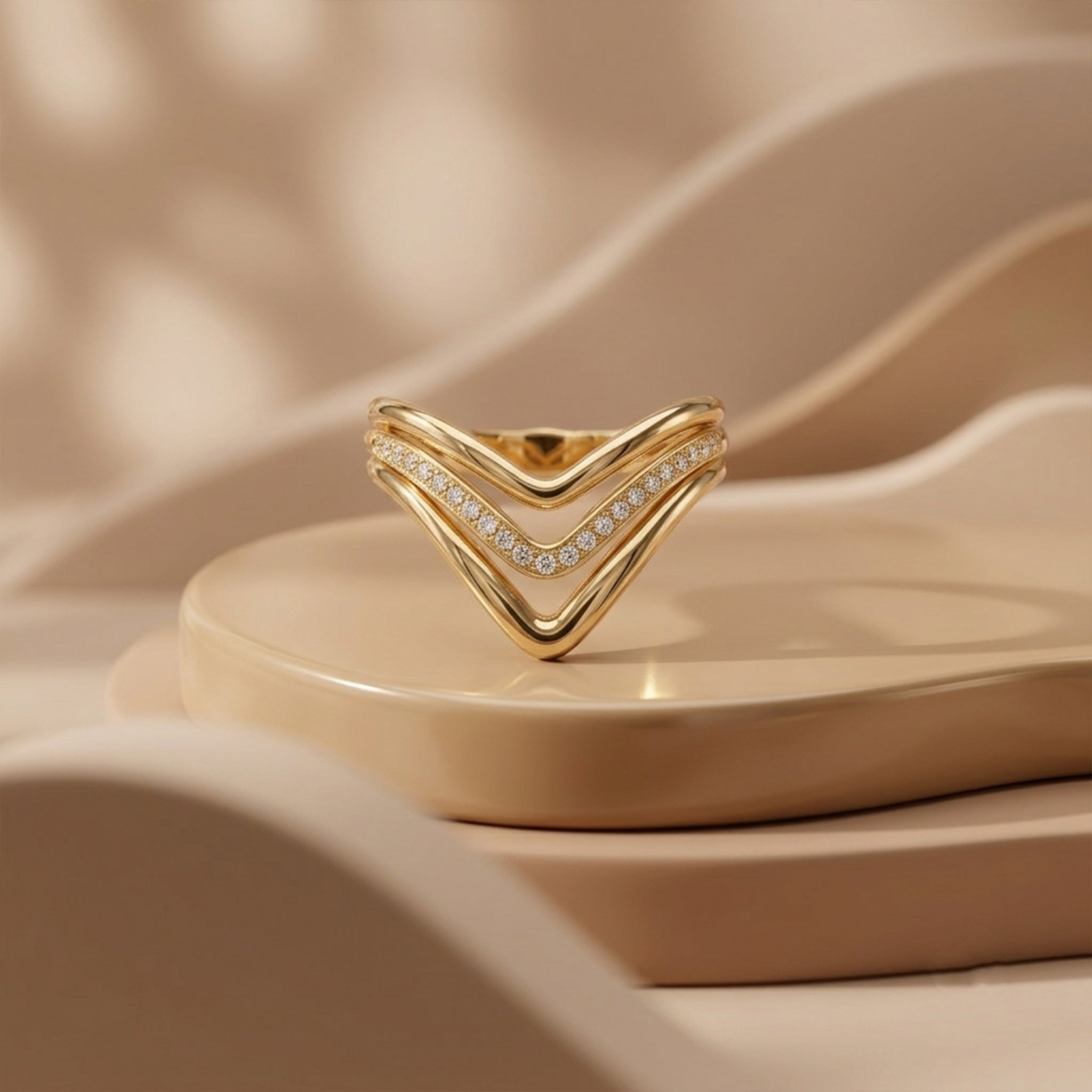 UNO 18k yellow gold V-shaped ring displayed upside down on modern beige curved pedestals under soft luxury studio lighting.
خاتم أونو دهب عيار 18 بتصميم V معروض بشكل مقلوب على قواعد بيج فخمة وتصميم مودرن.