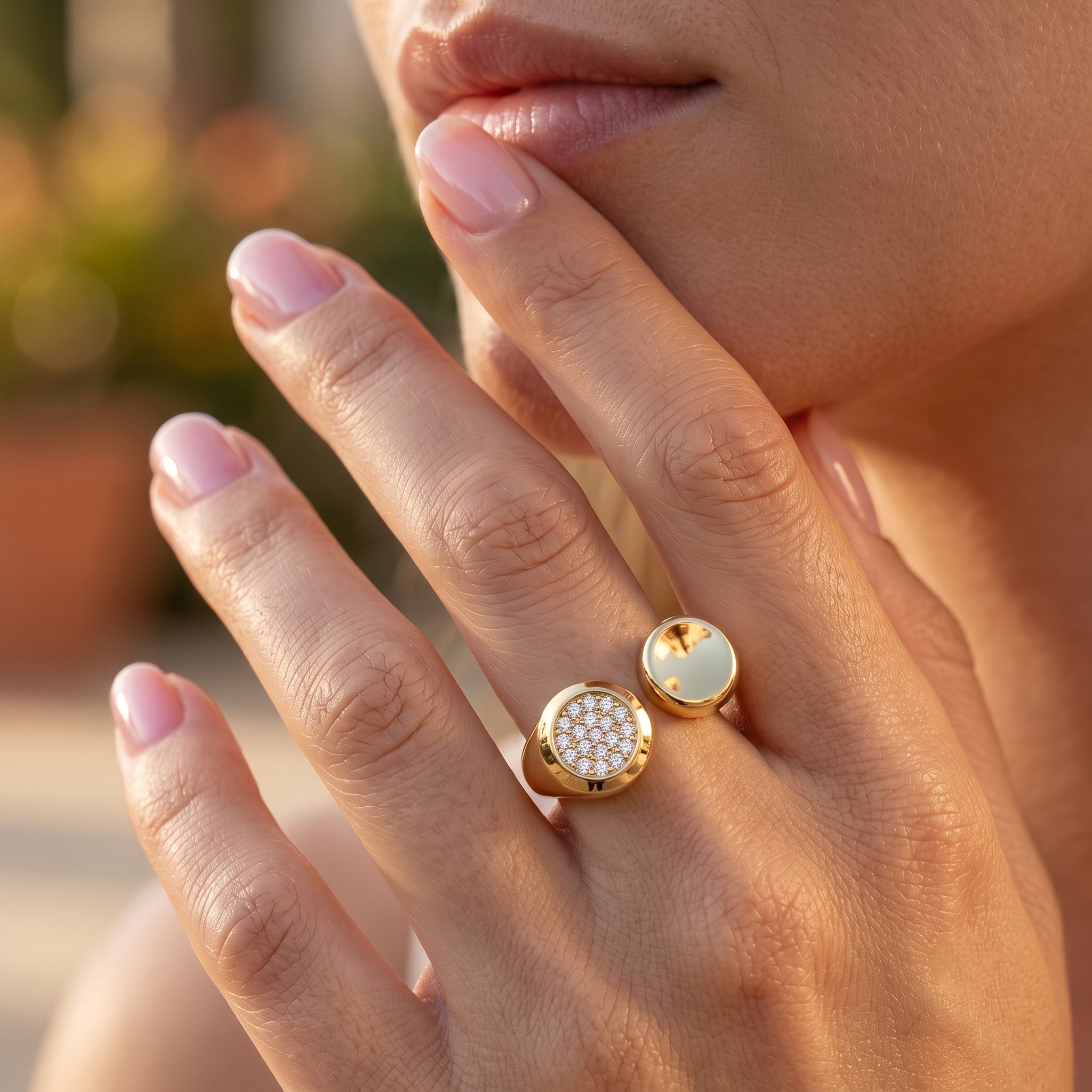 Close-up macro shot of the UNO 18k yellow gold open ring on a woman's hand, showcasing the contrasting smooth gold and stone-paved circular ends.
صورة قريبة لخاتم أونو المفتوح دهب عيار 18 على إيد موديل، بتبين التباين بين الدائرة السادة والدائرة اللي كلها فصوص.