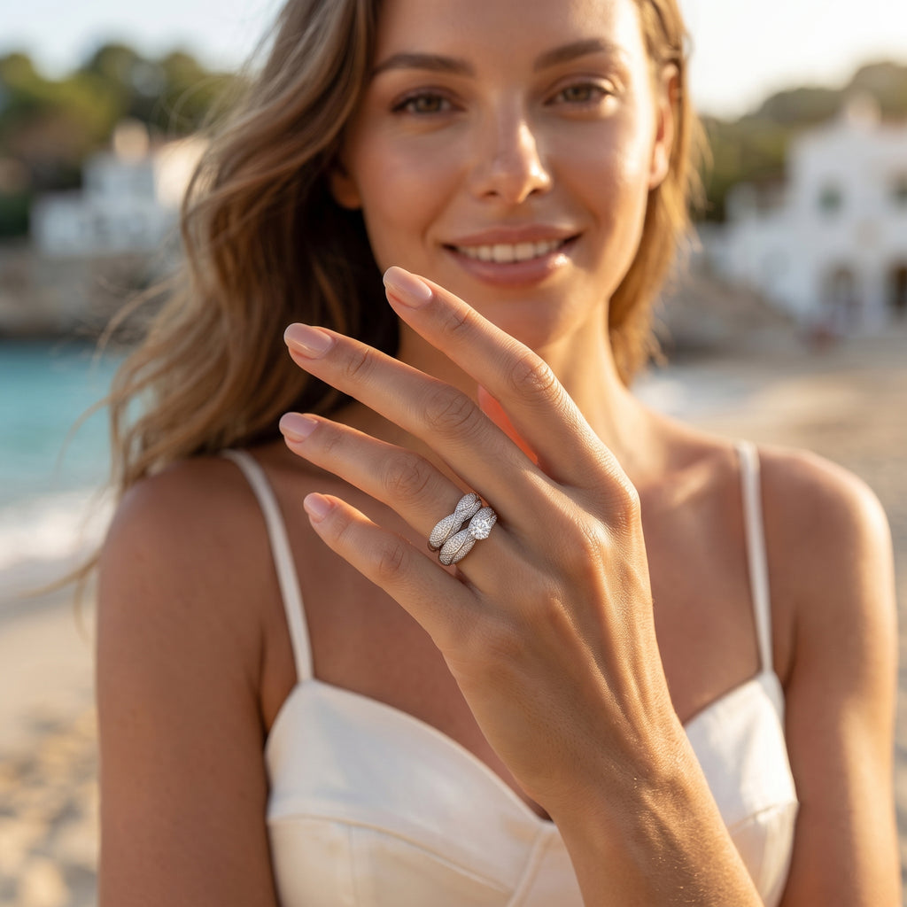 Lifestyle portrait of a woman in an ivory dress wearing the 10.36g L'azurde 18k white gold twin ring set on a Mediterranean coast.	عارضة أزياء ترتدي طقم خواتم توينز ذهب أبيض عيار 18 من لازوردي في مشهد صيفي ساحر على ساحل البحر.