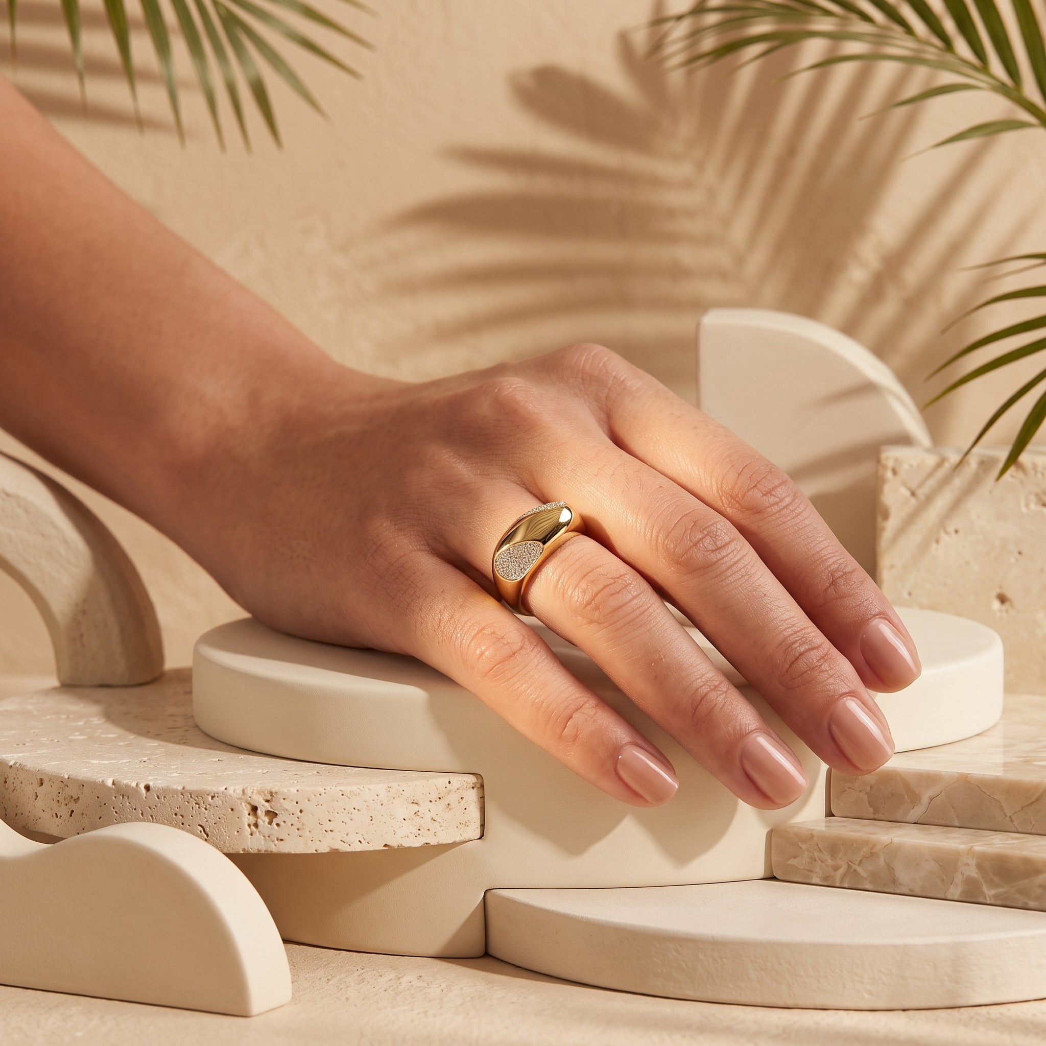 Fine Gold 18k yellow gold pavé ring (4.55g) on a feminine hand resting on a sculptural plaster pedestal with tropical palm shadows. خاتم فاين جولد ذهب عيار 18 (4.55 جرام) على يد رقيقة تستريح على منصة منحوتة مع ظلال أوراق النخيل الاستوائية.