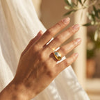 Close-up of a woman's hand gently moving in warm summer sunlight, wearing a 2.93g Remas Gold 18k geometric ring. لقطة مقربة ليد امرأة تتحرك بلطف في ضوء شمس الصيف الدافئ وترتدي خاتم ريماس جولد هندسي عيار 18 بوزن 2.93 جرام.