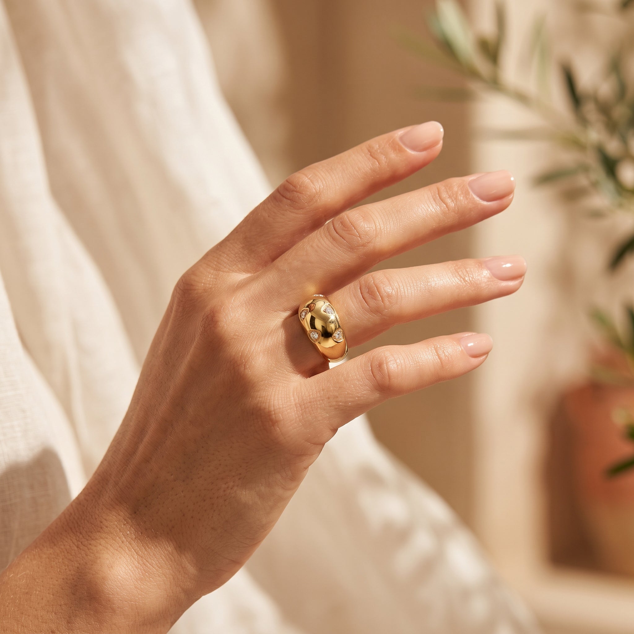 Close-up of a woman's hand in warm summer sunlight wearing a 4g L'azurde 18k gold dome ring. لقطة مقربة ليد امرأة في ضوء شمس الصيف الدافئ ترتدي خاتم لازوردي بومبيه ذهب عيار 18 بوزن 4 جرام.