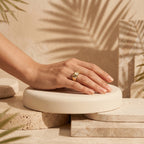 4g L'azurde gold dome ring on a woman's hand resting on a sculptural pedestal with tropical shadows. خاتم لازوردي ذهب بومبيه بوزن 4 جرام على يد امرأة تستريح على منصة منحوتة مع ظلال استوائية.
