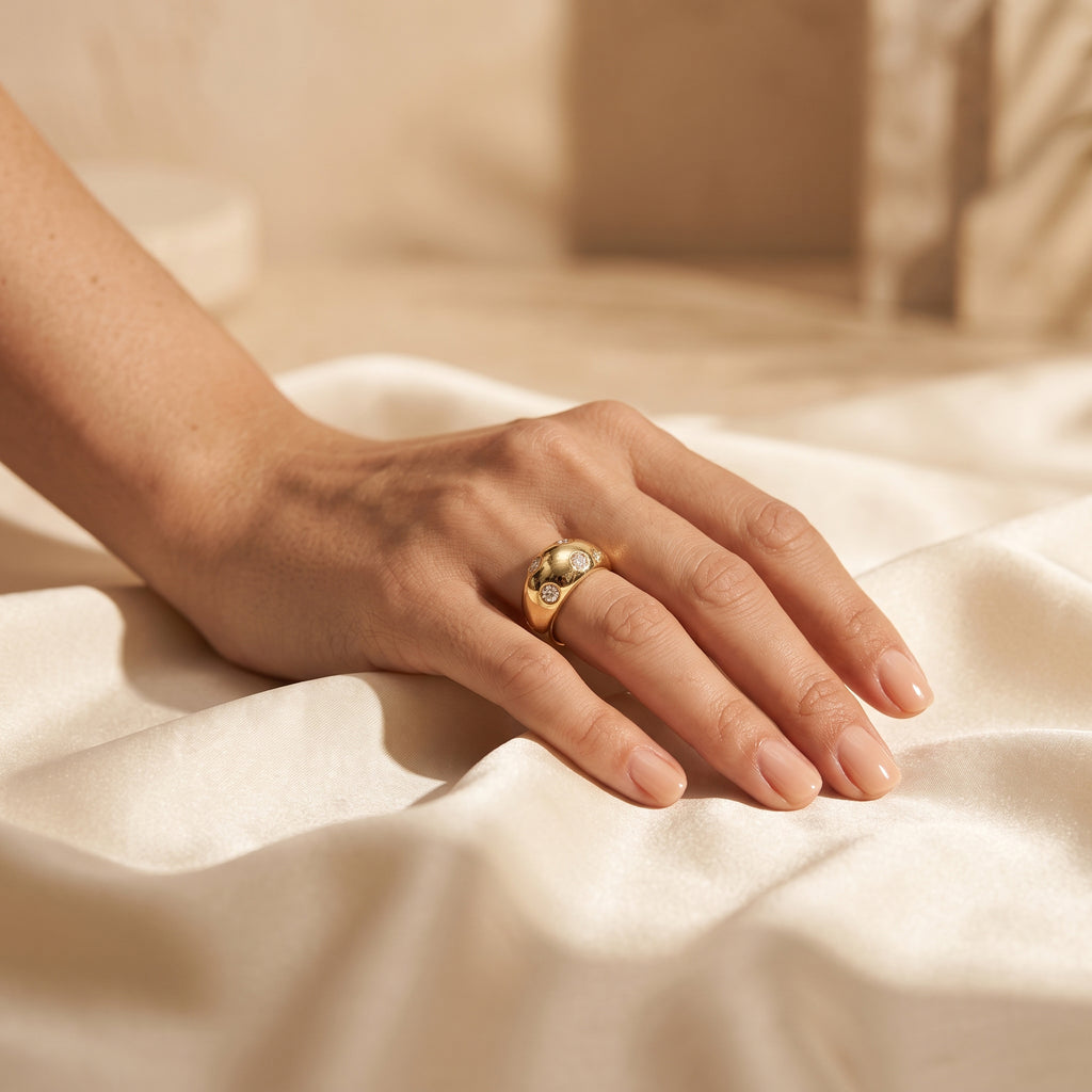 L'azurde 18k gold scattered gem ring (4g) on a woman's hand resting elegantly on warm ivory silk. خاتم لازوردي ذهب عيار 18 مرصع (4 جرام) على يد امرأة تستريح بأناقة على قماش حرير عاجي دافئ.