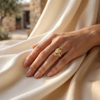 Andria gold ring on a woman's hand resting gracefully on luxurious ivory silk.	خاتم أندريا الذهبي على يد امرأة تستريح بنعومة على قماش حرير عاجي فاخر.