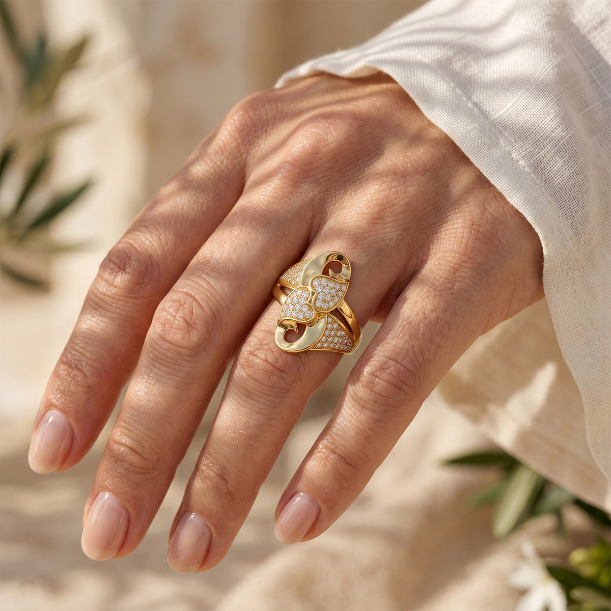 Close-up of a woman's hand wearing the Andria gold heart ring in warm summer sunlight.	لقطة مقربة ليد امرأة ترتدي خاتم أندريا الذهبي تحت أشعة شمس الصيف الدافئة.