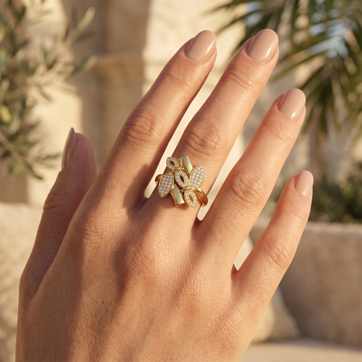 Close-up of a woman's hand wearing the Fine Gold floral ring in warm sunlight.	لقطة مقربة ليد امرأة ترتدي خاتم فاين جولد بتصميم زهرة تحت أشعة الشمس الدافئة.