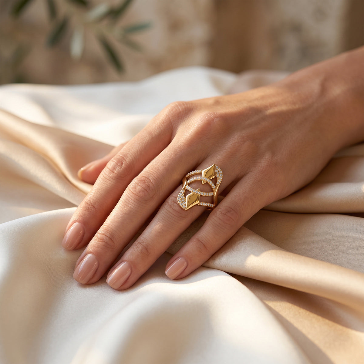 Fine Gold abstract ring on a woman's hand resting gracefully on luxurious ivory silk.	خاتم فاين جولد الذهبي على يد امرأة تستريح بنعومة على قماش حرير عاجي فاخر.