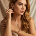 Woman wearing gold jewelry set with green gemstones against a beige background