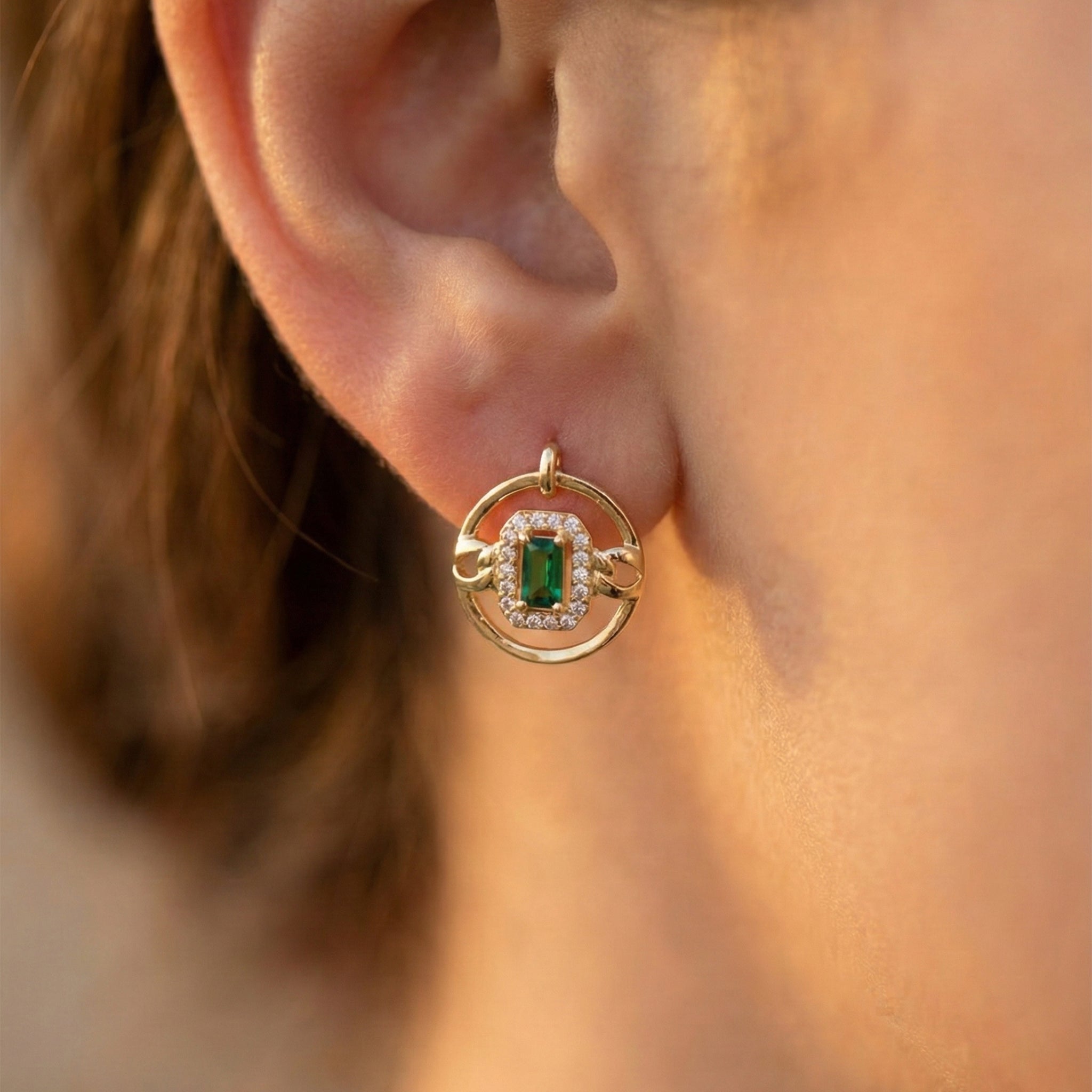 Gold earring with a green gemstone worn by a person