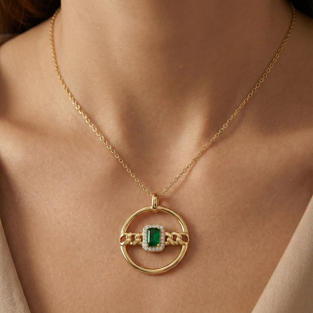 Gold necklace with a green gemstone pendant on a person's neck