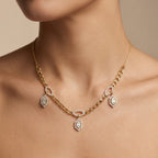 Gold necklace with diamond pendants on a person against a neutral background