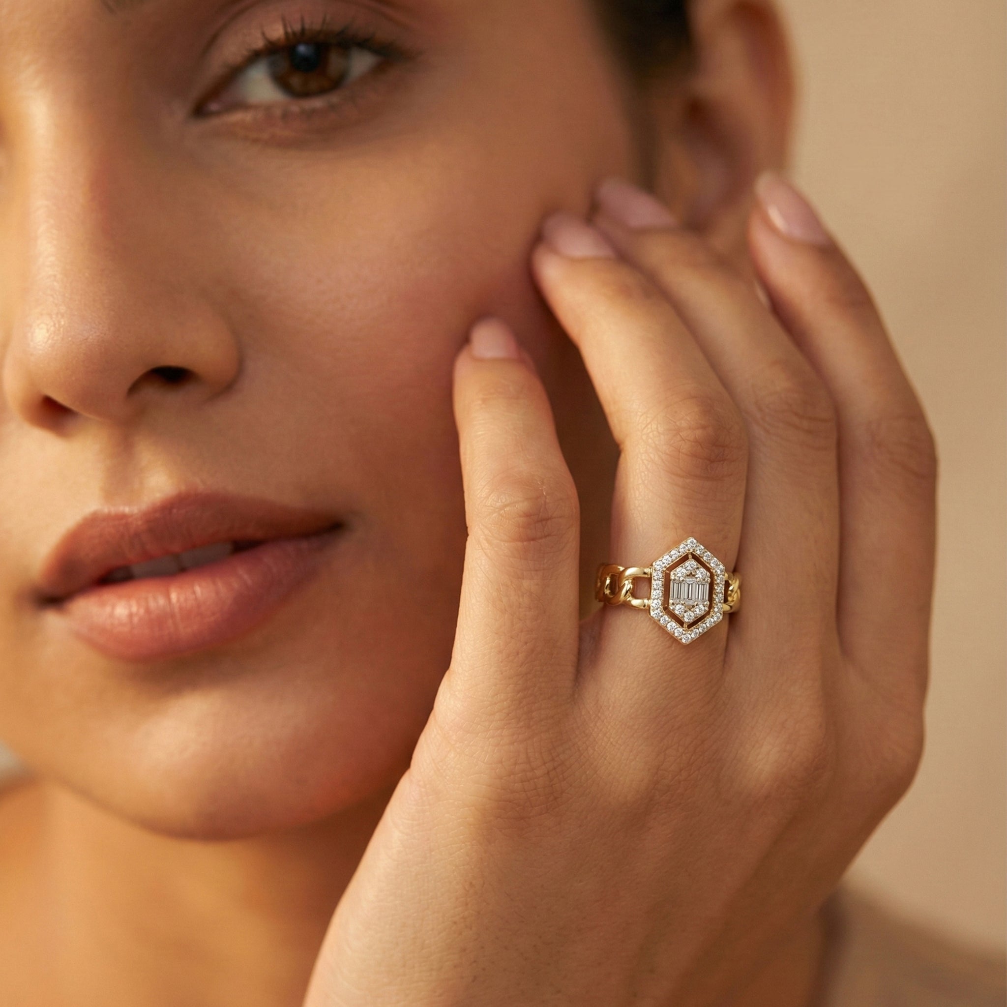 Close-up of a woman's face wearing a gold ring with a diamond, against a neutral background.