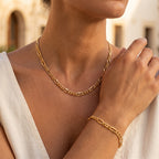 Close-up of a woman wearing a L'azurde 18K gold Gourmet chain necklace and matching bracelet.	لقطة قريبة لامرأة ترتدي سلسلة ذهب جرميت عيار 18 من لازوردي مع سوار مطابق على معصمها.