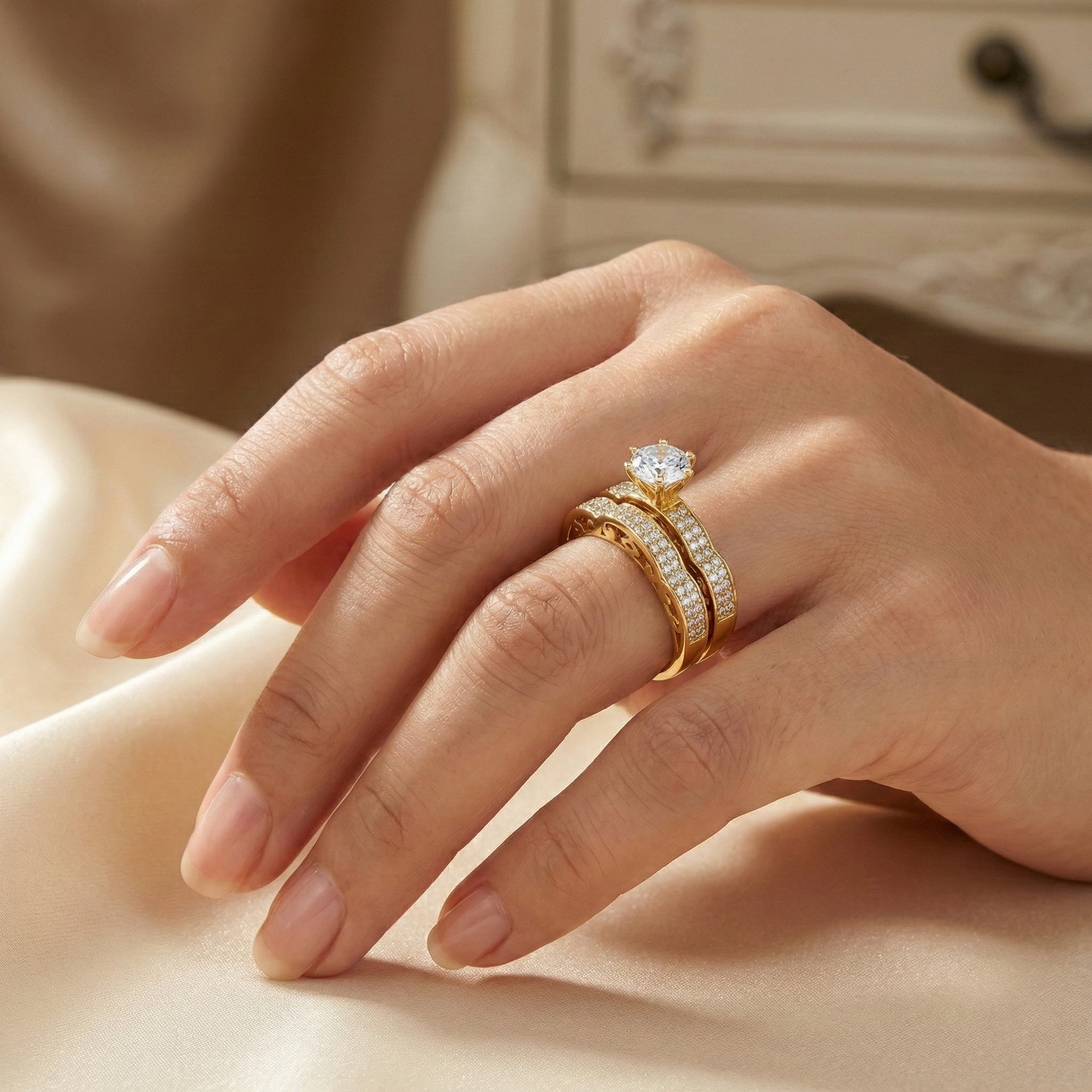 Hand wearing a gold ring with a diamond on a soft fabric background