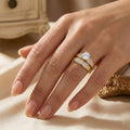 Hand wearing a gold ring with a diamond on a beige surface