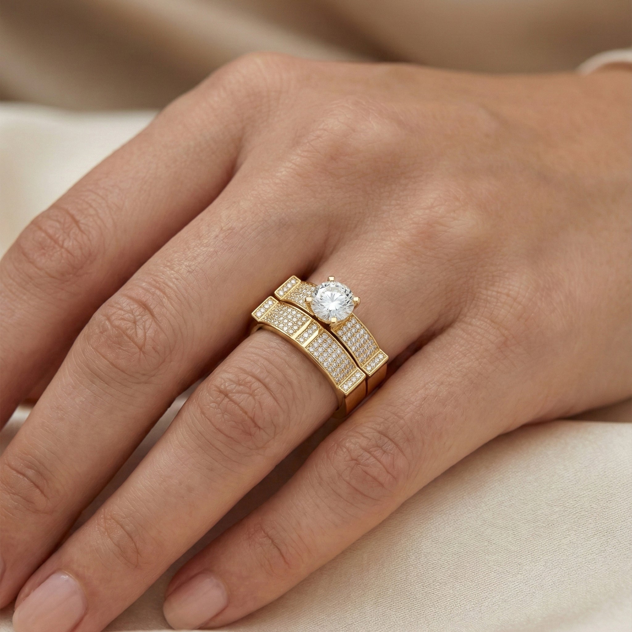 Gold ring with a diamond on a person's finger against a beige background