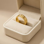 Gold ring in a jewelry box on a beige background