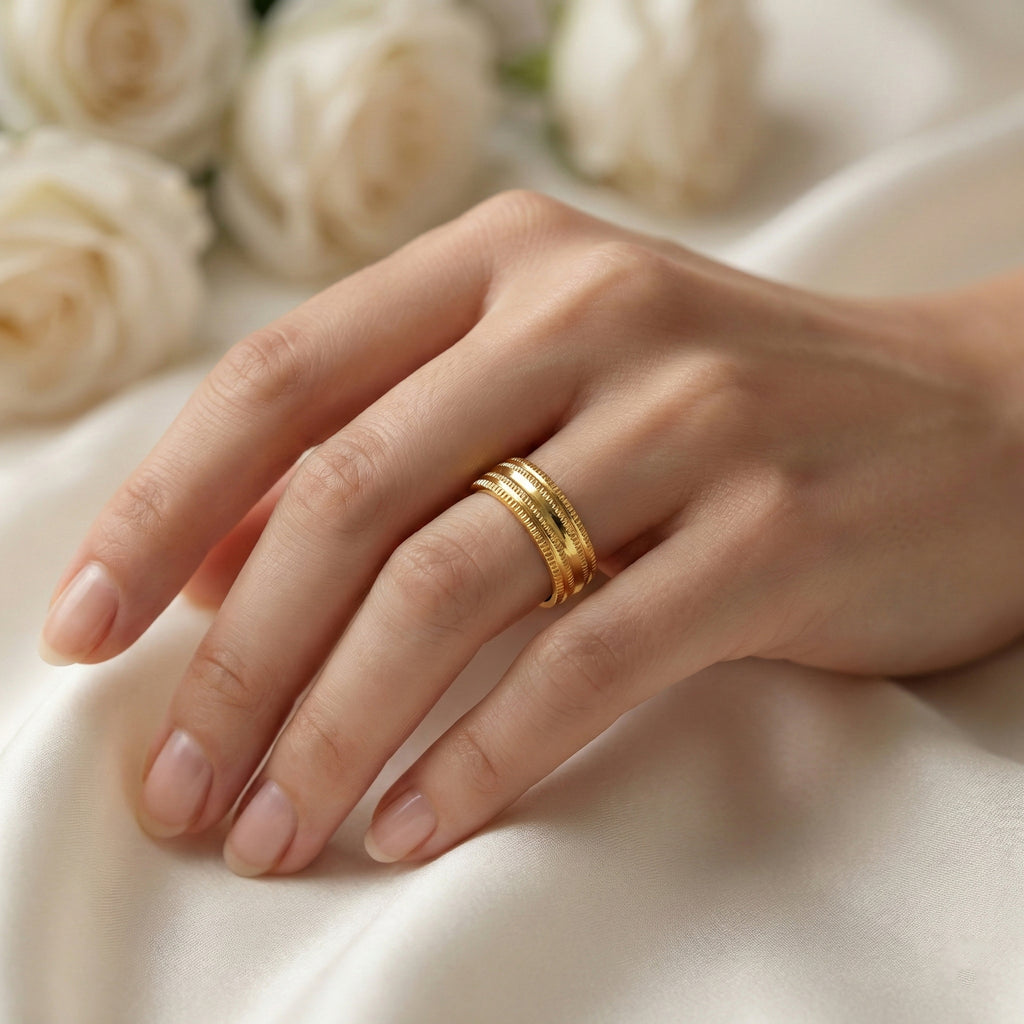Hand wearing a gold ring with white roses in the background