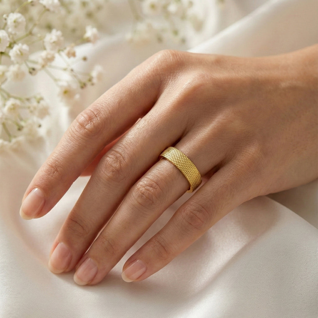 Hand wearing a gold ring with a soft white background