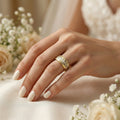 Hand wearing a gold ring with flowers in the background