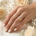Hand wearing two gold rings with a diamond on a floral background
