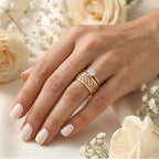 Hand wearing two gold rings with a diamond on a floral background
