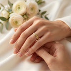 Close-up of hands with a gold ring, surrounded by white flowers on a light background